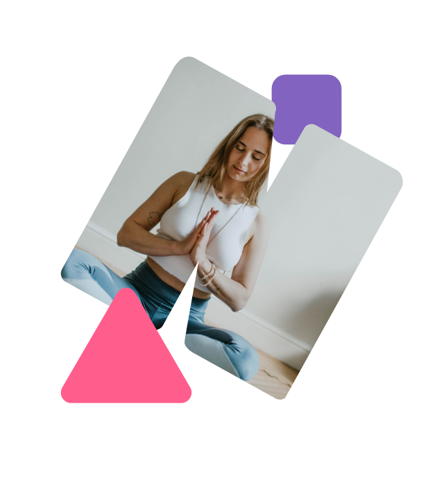 Eine Frau sitzt im Schneindersitz auf dem Boden. Ihre Augen sind geschlossen und sie hat die Hände vor der Brust zusammengelegt.