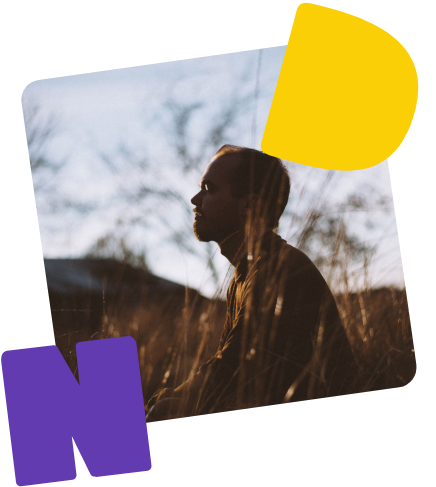 Mann im Profil. Er sitzt mit geschlossenen Augen in einem Weizenfeld.