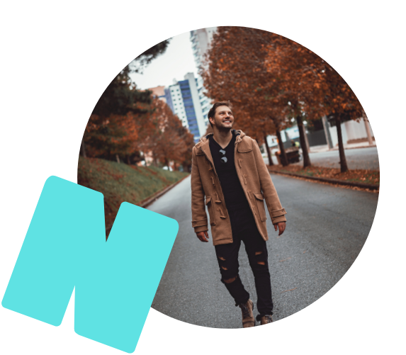 Ein Mann in einem braunen Mantel geht lachend die Straße entlang.