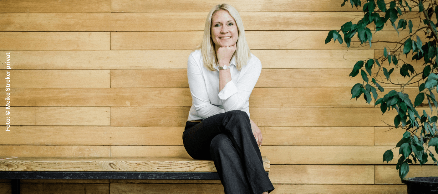 Dr. Mareike Streker; junge blonde Frau sitzt vor einer Holzwand